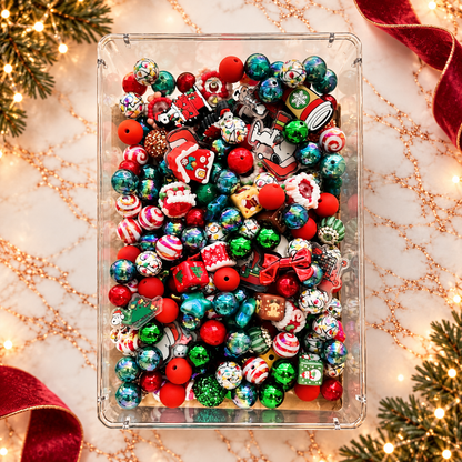 Overhead view of Christmas Mix beads in a clear rectangular tray, featuring red and green rounds, peppermint-striped beads, multicolored Christmas-light patterns, decorated houses, holiday characters, bows, gift and drink shapes, sparkling accents and other festive focal pieces.