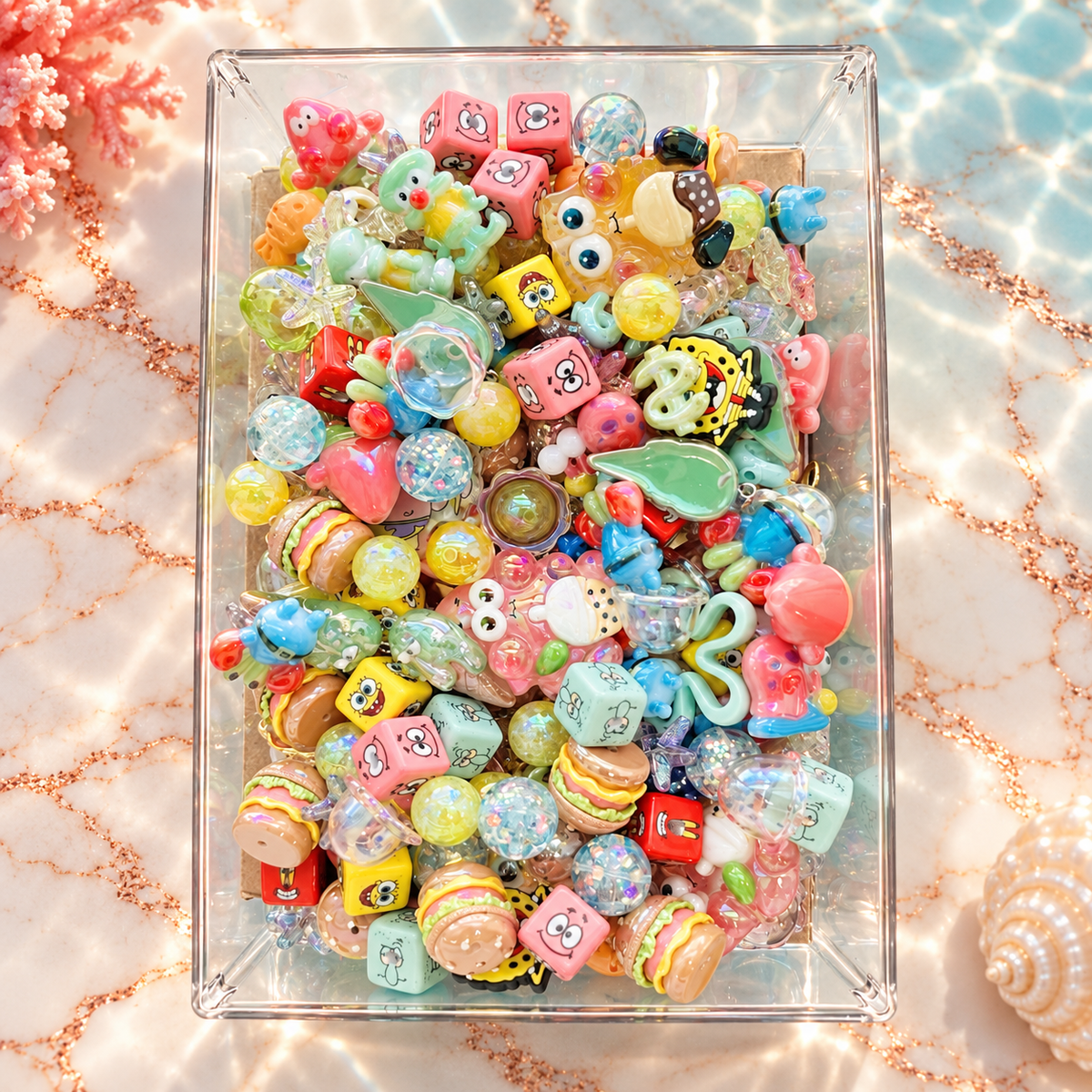 Overhead view of the Krabby Patty bead mix filling a clear tray, with colorful burger beads, character-inspired cubes, sea creatures, starfish, shells and translucent accent beads in pink, yellow, aqua, mint and blue.