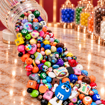 Close-up of the Chocolate Candies bead mix showing colorful candy-inspired rounds, heart-shaped beads, character cubes, cookie and candy focal pieces, glossy orange, green, blue, yellow and purple beads, and dimensional character-inspired accents.