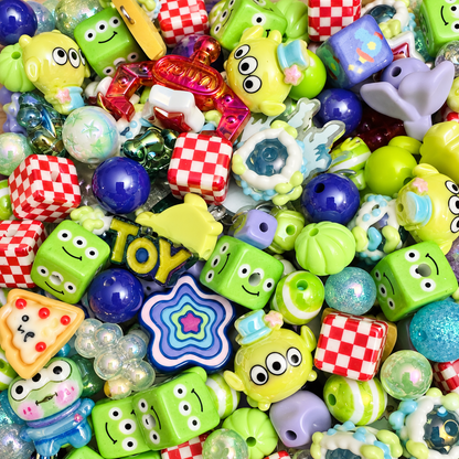 JAZ Bead Co. Pizza Planet bead mix in a clear jar with a rose-gold lid, filled with bright green alien-inspired characters, blue, lavender and aqua beads, red-and-white checkerboard cubes, stars and pizza-shaped focal pieces, displayed in a retro pizza restaurant setting.