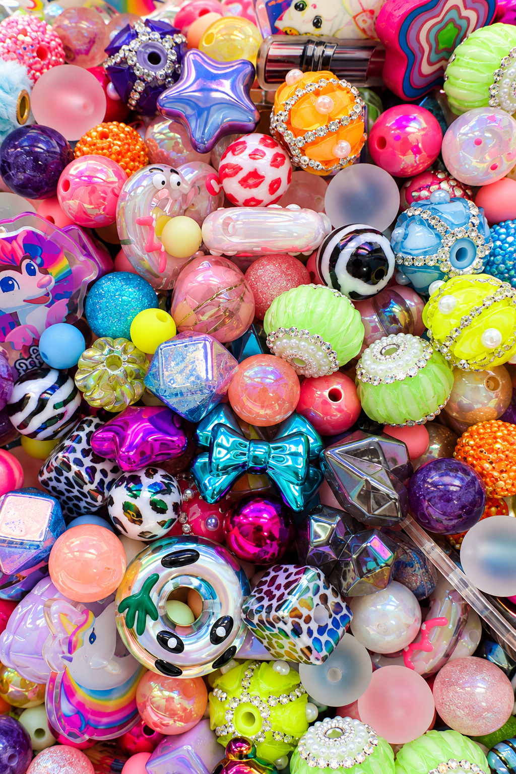 Close-up of the Cosmic Crush bead mix showing glossy and glittered rounds, iridescent stars and geometric beads, metallic bows, animal prints, rhinestone and pearl details, frosted beads and colorful novelty focal pieces.