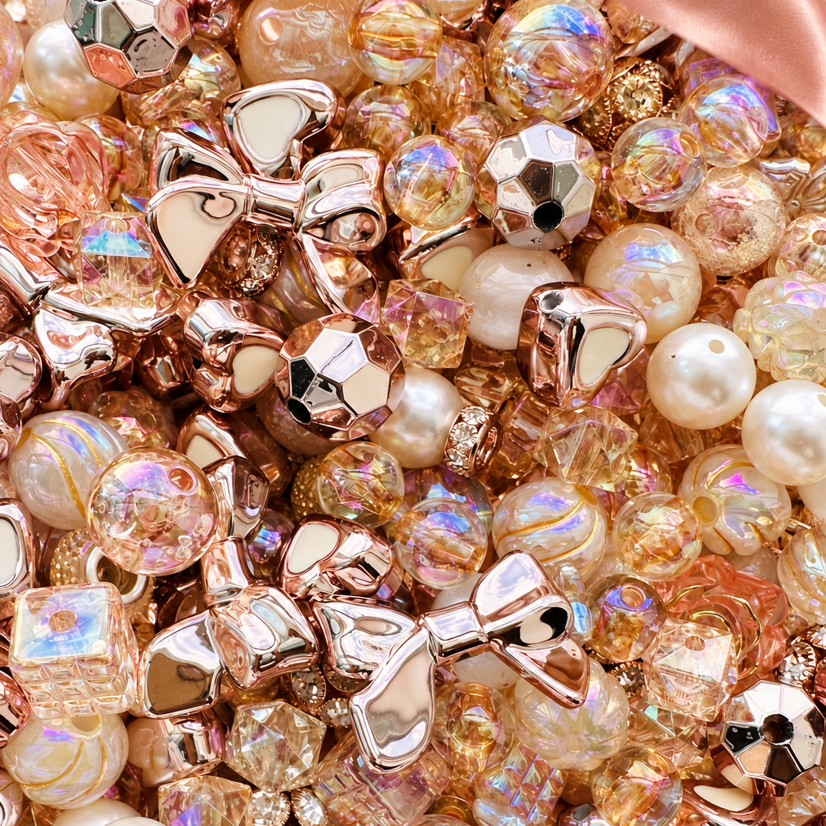 Close-up of Rose Gold bead mix highlighting reflective rose-gold bow beads, creamy pearls, champagne iridescent rounds, faceted crystal-look beads, geometric metallic shapes and warm translucent accents.